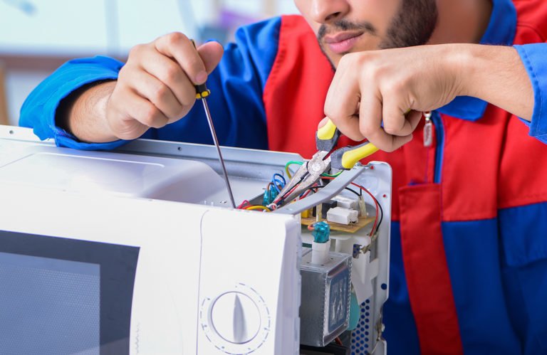 Small appliance repair man fixing a microwave